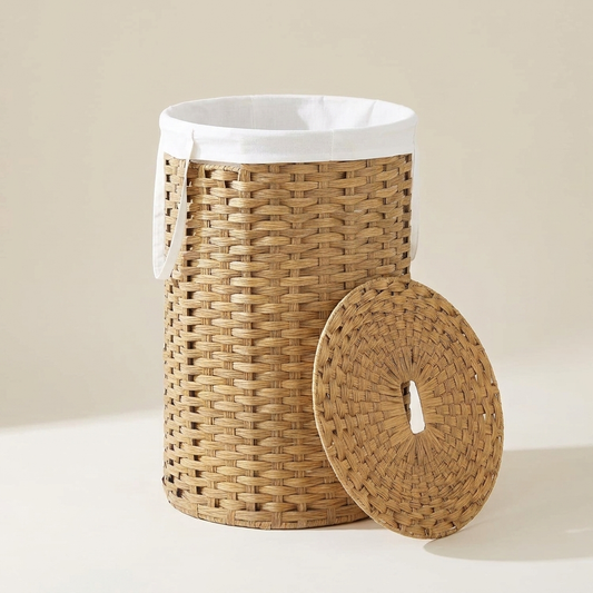 Handwoven wicker laundry hamper with side handles on a warm neutral background.